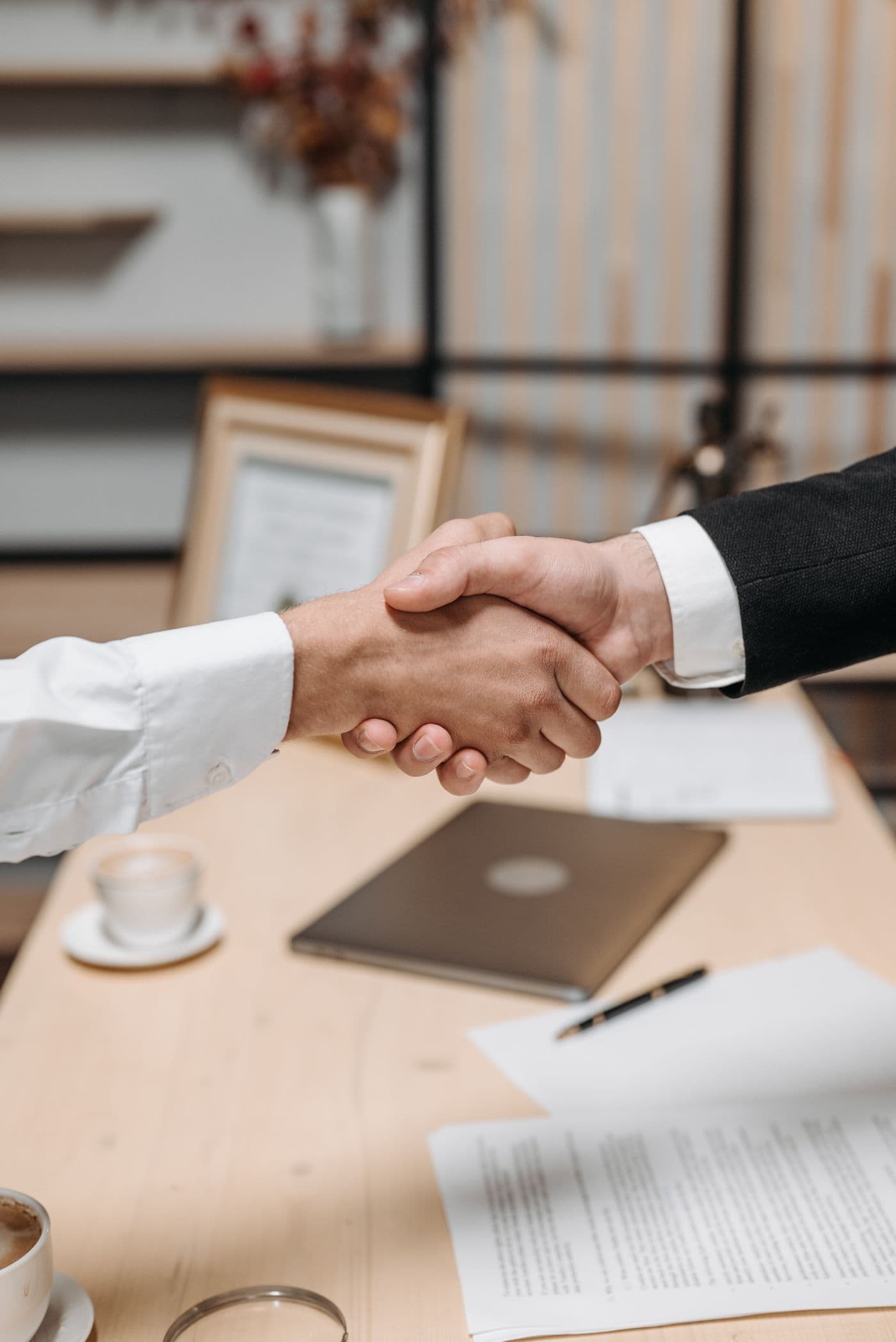 Two professionals shaking hands over a desk