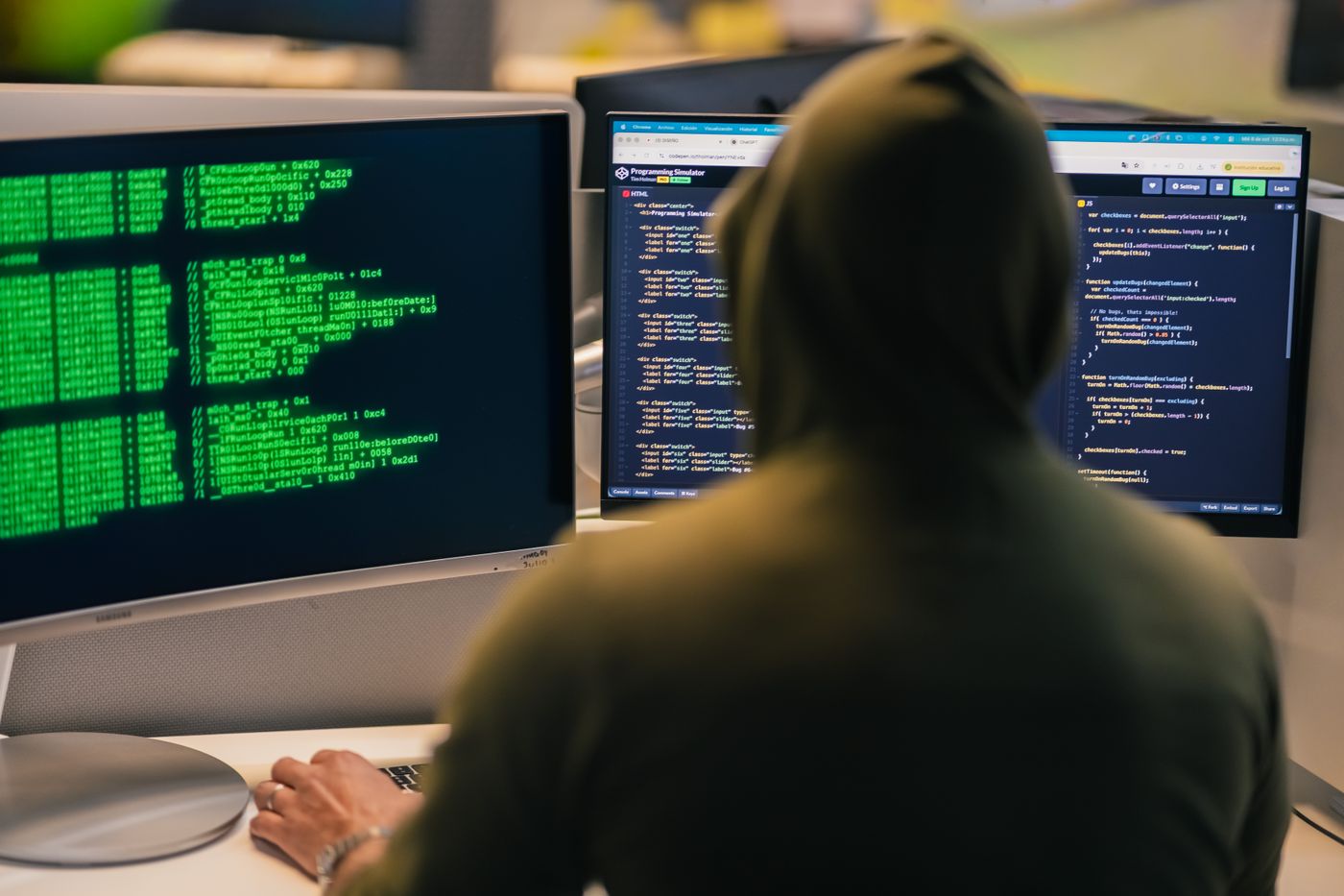 Developer seen from behind working in terminals on multiple monitors
